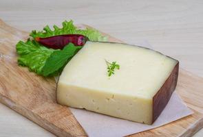 Hard cheese on wooden board and wooden background photo