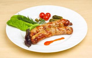 Grilled sausages on the plate and wooden background photo