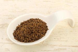 Caraway pile in a bowl on wooden background photo