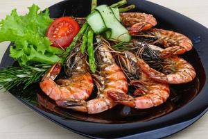 Grilled prawns on the plate and wooden background photo