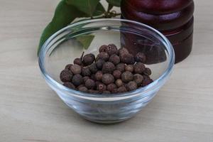 Pepper mill in a bowl on wooden background photo