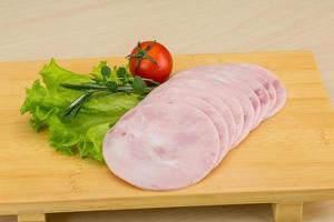 Sliced ham on wooden board and wooden background photo