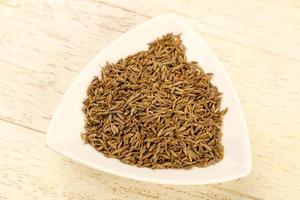 Cumin seeds in a bowl on wooden background photo