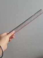A hand is holding a plastic ruler. photo