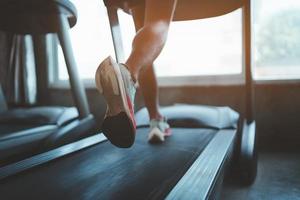 Close up of feet, sportman runner running on treadmill in fitness club. Cardio workout. Healthy lifestyle, guy training in gym. Sport running concept photo