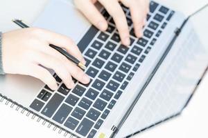 Woman working at home office using laptop searching web, browsing information photo