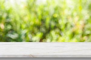 Marble table top with blur green leaf bokeh nature background photo