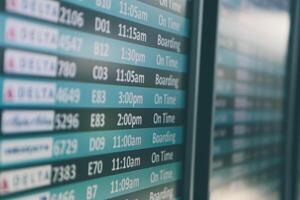 Airport departures timetable showing Delta and Alaska Airlines flights on time and boarding photo