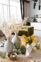 Festive Easter table with mimosa flowers in a vase and traditional food, eggs. The interior of a bright living room with a round set table photo