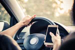 primer plano de una mujer enviando mensajes de texto por teléfono móvil mientras conduce un automóvil. foto