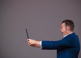 Furious businessman screaming while using touchpad. photo