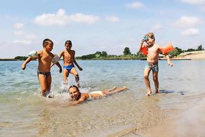 madre feliz divirtiéndose con sus hijos en la playa, foto