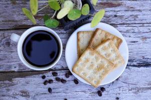 The hot black coffee in a white cup and the crackers are intense and go well together. photo