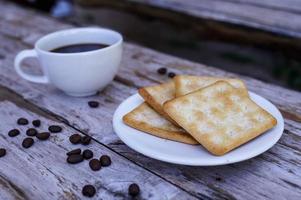 The hot black coffee in a white cup and the crackers are intense and go well together. photo