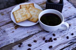 The hot black coffee in a white cup and the crackers are intense and go well together. photo