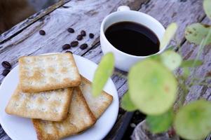 The hot black coffee in a white cup and the crackers are intense and go well together. photo