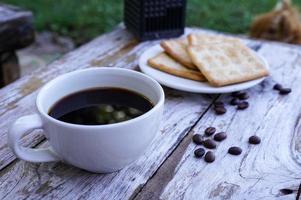 The hot black coffee in a white cup and the crackers are intense and go well together. photo