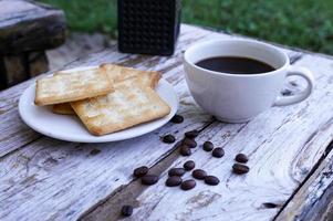 The hot black coffee in a white cup and the crackers are intense and go well together. photo