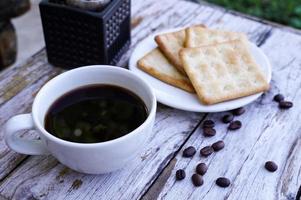 The hot black coffee in a white cup and the crackers are intense and go well together. photo