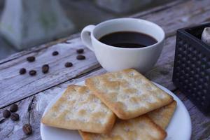 The hot black coffee in a white cup and the crackers are intense and go well together. photo
