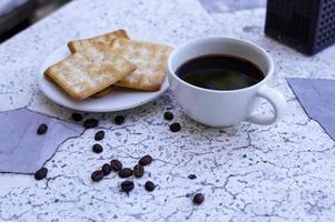 The hot black coffee in a white cup and the crackers are intense and go well together. photo