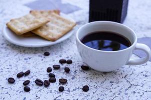 The hot black coffee in a white cup and the crackers are intense and go well together. photo