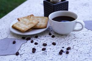 The hot black coffee in a white cup and the crackers are intense and go well together. photo