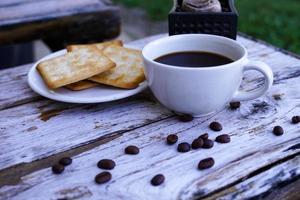 el café negro caliente en una taza blanca y las galletas son intensos y van bien juntos. foto