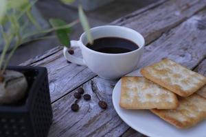 The hot black coffee in a white cup and the crackers are intense and go well together. photo