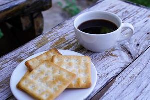 The hot black coffee in a white cup and the crackers are intense and go well together. photo