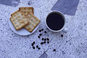 The hot black coffee in a white cup and the crackers are intense and go well together. photo