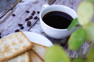 The hot black coffee in a white cup and the crackers are intense and go well together. photo