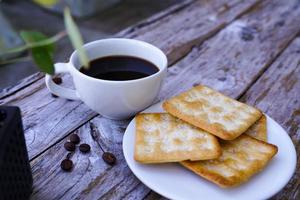 The hot black coffee in a white cup and the crackers are intense and go well together. photo