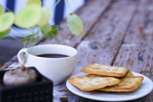 The hot black coffee in a white cup and the crackers are intense and go well together. photo
