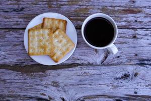 The hot black coffee in a white cup and the crackers are intense and go well together. photo