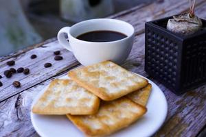 The hot black coffee in a white cup and the crackers are intense and go well together. photo