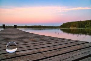 Glass ball on a wooden pier at a Swedish lake at evening hour. Nature Scandinavia photo