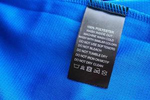 Black laundry care washing instructions clothes label on blue jersey polyester sport shirt photo