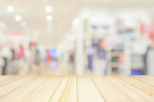 Empty wood table top with modern clothing store interior blur abstract defocused background with bokeh light for product display photo