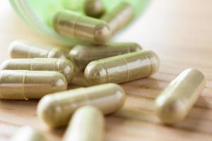 Herbal medicine capsules with bottle on wood table photo