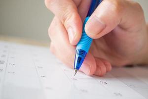 Woman hand with pen writing on calendar date business planning appointment meeting concept photo