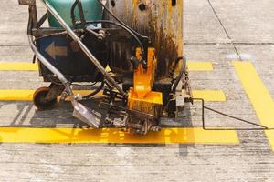 primer plano de la máquina de marcado por pulverización termoplástica que hace líneas para pintar las líneas de tráfico en la carretera asfaltada. foto