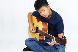 niño o adolescente tocando guitarra acústica sobre fondo blanco. concepto de aprendizaje y relajación. foto