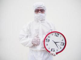 Portrait of doctor or scientist in PPE suite uniform holding red alarm clock and looking at the camera In various gestures. COVID-19 concept isolated white background photo