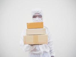 joven con uniforme de suite de ppe mientras sostiene cajas de cartón con guantes médicos de goma y máscara. concepto de coronavirus o covid-19 fondo blanco aislado foto