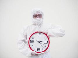 Portrait of doctor or scientist in PPE suite uniform holding red alarm clock and looking at the camera In various gestures. COVID-19 concept isolated white background photo