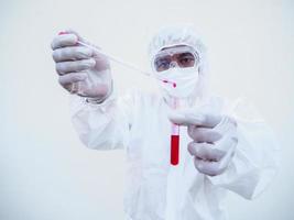 Asian doctor or scientist in PPE suite uniform. Personal protective equipment suit dropping a blood into blood test tube. coronavirus or COVID-19 concept isolated white background photo