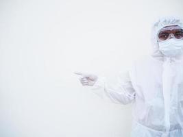 Asian male doctor or scientist in PPE suite uniform showing pointing fingers away at copy space while standing and looking forward. coronavirus or COVID-19 concept isolated white background photo