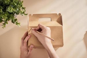 Cropped image of woman writing best wishes on box with present photo