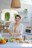 Pretty young woman chef putting salt in a salad photo